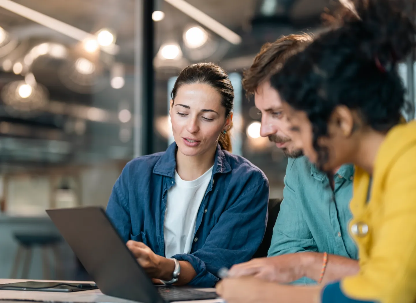 Team collaborating over a tablet, symbolizing skills built in the Finance Certificate program.