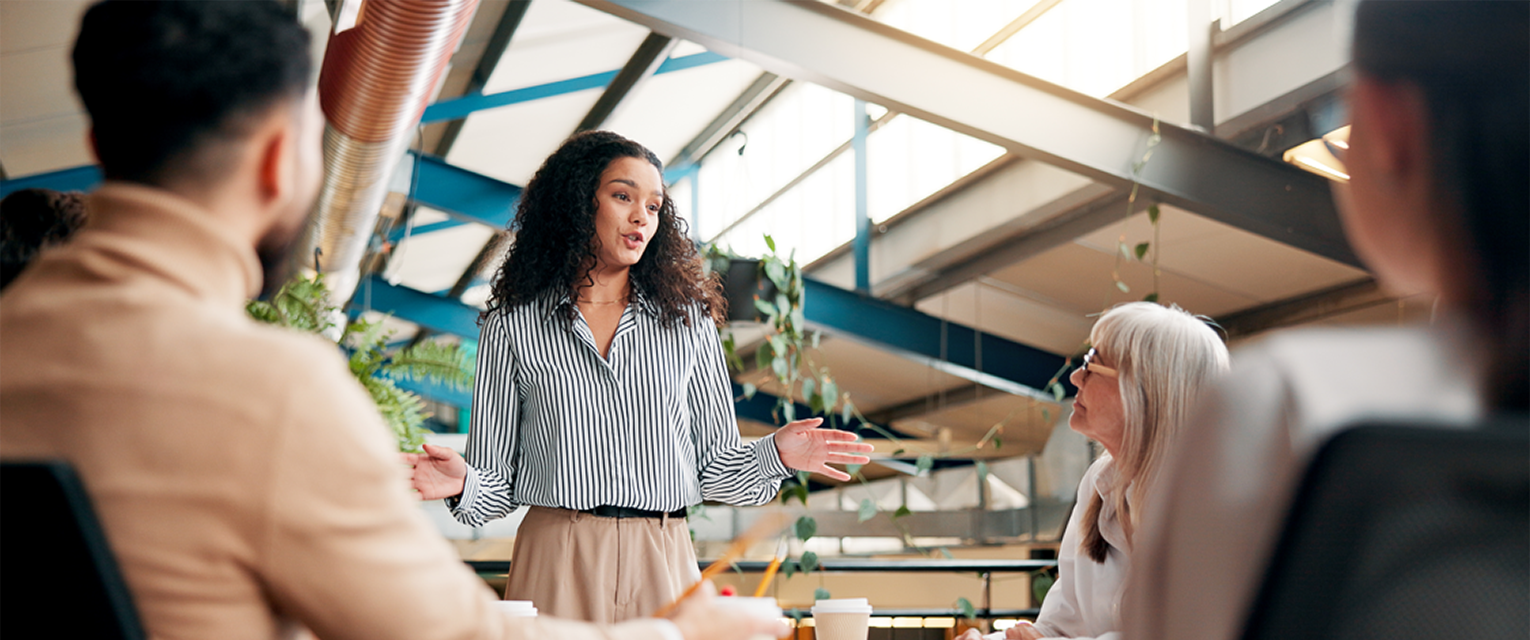 A business professional is leading a meeting in a warehouse coworking space.