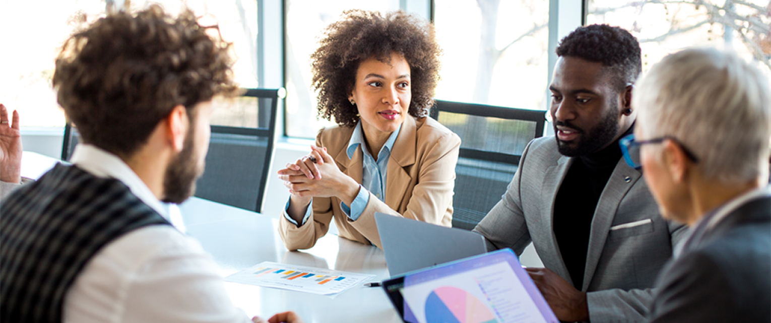Several business professionals are meeting around a conference room table.